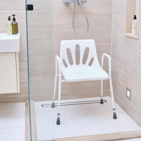 The shower chair placed in a bathroom shower, demonstrating its durable steel frame, drainage holes in the seat for water flow, and anti-slip rubber ferrules for added stability during use.